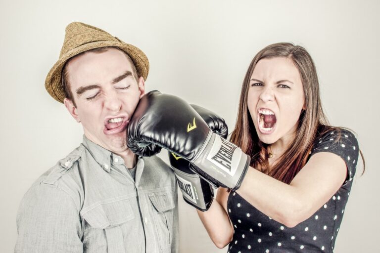 Woman wearing boxing gloves and punch a man in the face
